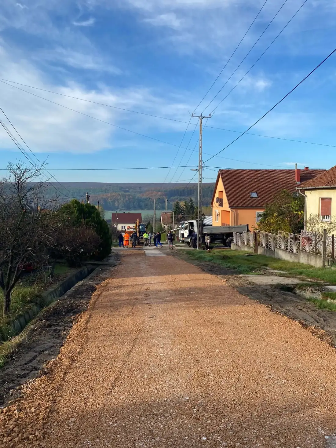 Zúzottkő alapréteg terítése falusi utcában — útépítés Győr térségében